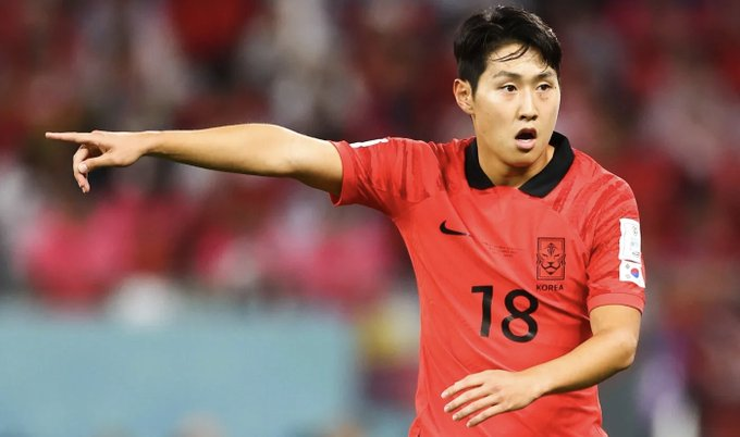 South Korea soccer player in a red jersey number 18 pointing to the left during a match on the field.