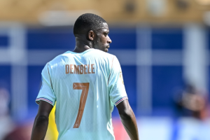 Soccer player, back view, wearing light blue jersey with the name 'DEMBELE' and number 7 on the back on a sunny field.