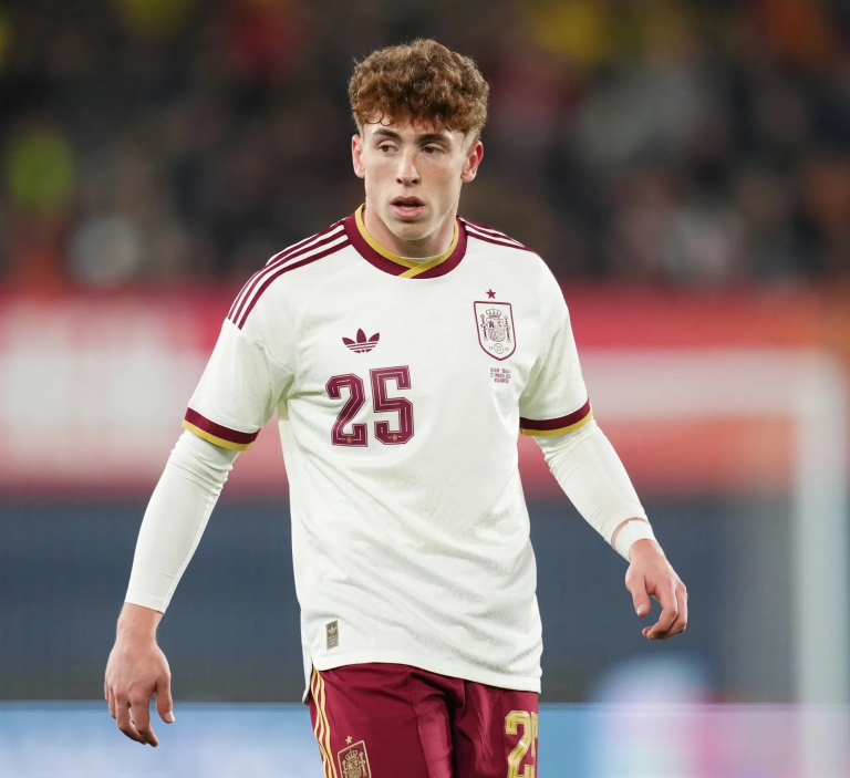 Spain national team footballer in a white jersey with maroon trim, number 25, on the field during a match.