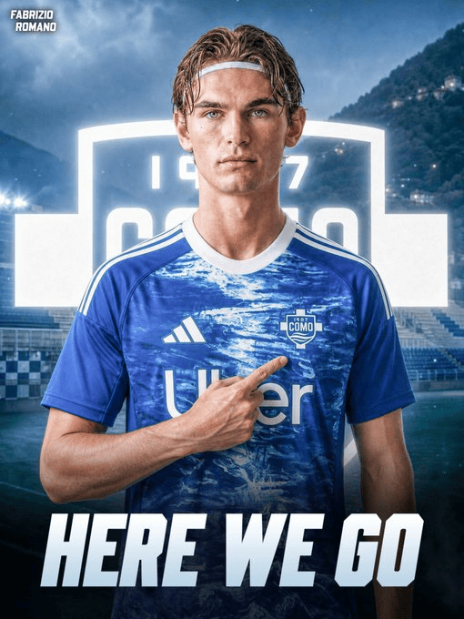Soccer player in a blue jersey in a stadium, pointing at the badge with 'HERE WE GO' at the bottom.