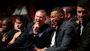 Group of formally dressed people laughing and chatting at a gala or formal event in dim lighting, front rows seated together