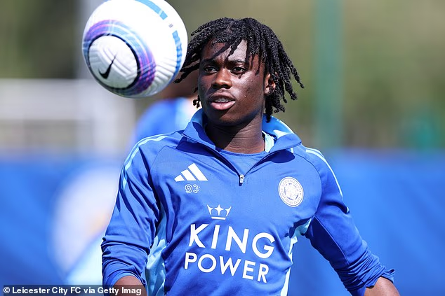 Footballer wearing a blue training kit heads a ball during practice on a sports field.