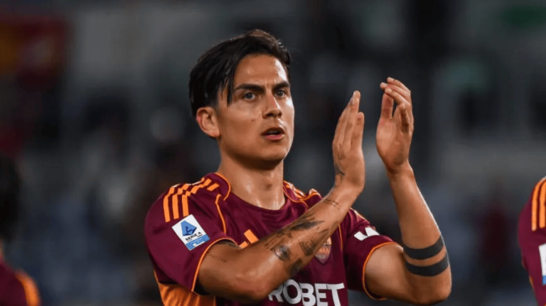 Soccer player in maroon and orange Roma kit applauding on the field after a match.