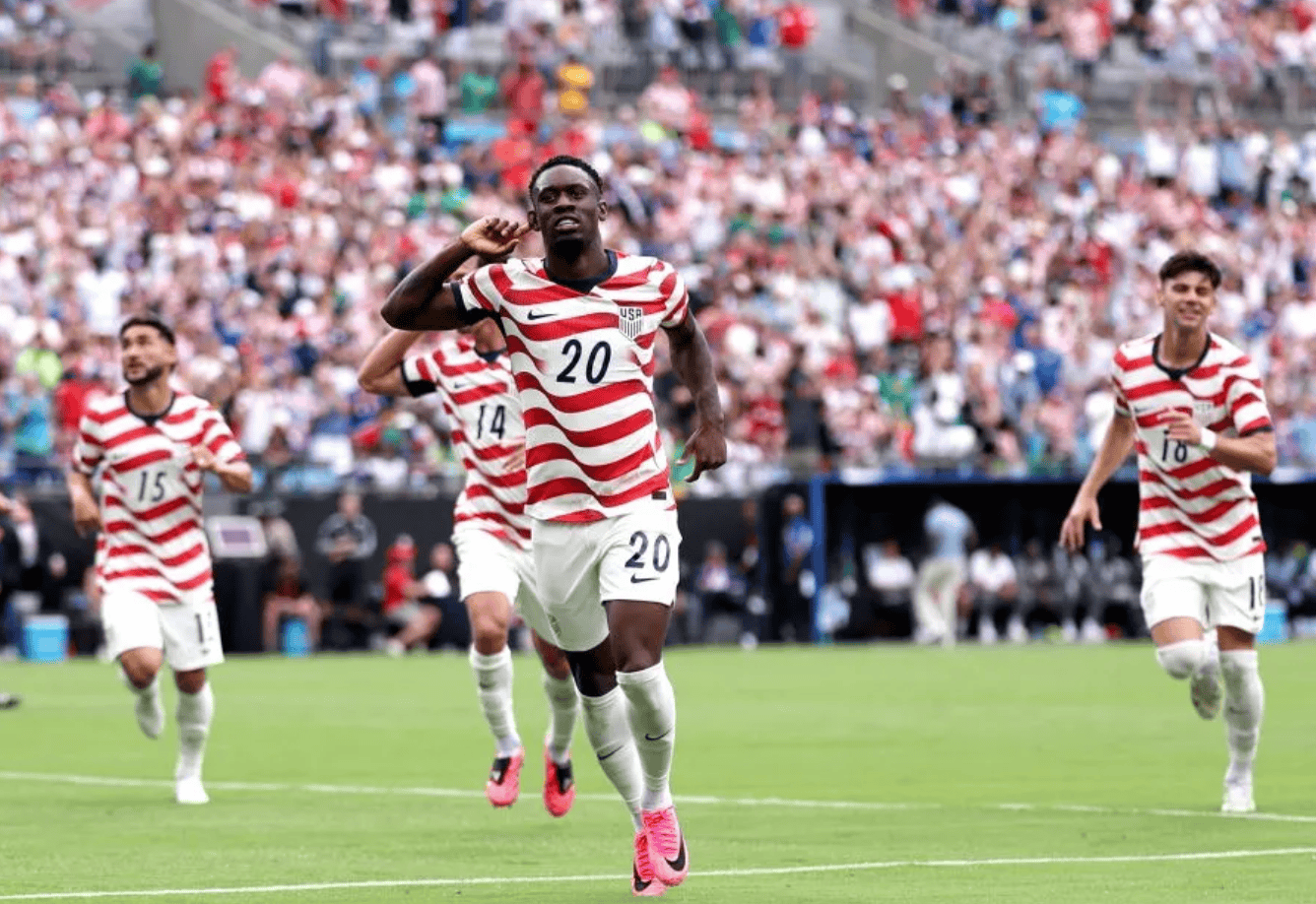 hupu-football-1781344596933-ayx-1png - AYX Sports Hub USA soccer players in red-and-white striped jerseys celebrate on a green pitch as a packed stadium cheers.
