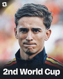 Close-up of a young male athlete with a determined expression, wearing a dark jacket with red, yellow, and blue stripes; '2nd World Cup' text at the bottom.