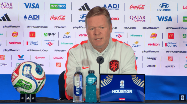 Press conference setup with Dutch national team coach at a FIFA backdrop, ball on a stand to the left and a laptop showing Houston 2026.