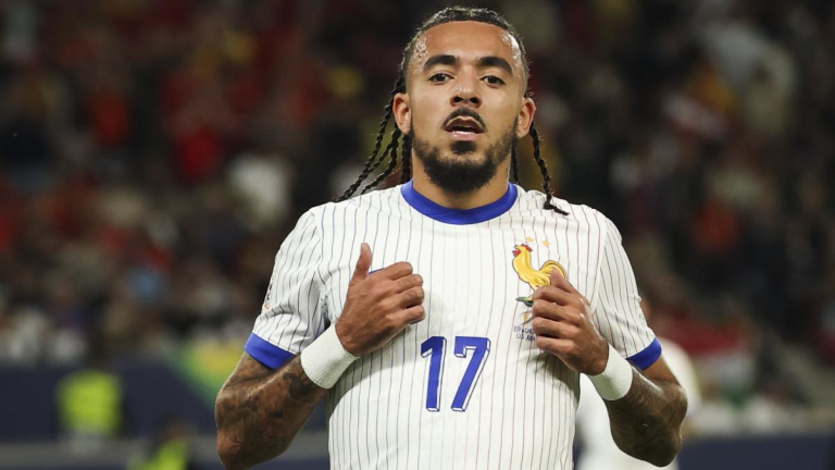 Soccer player wearing a white pinstripe jersey with blue trim and the number 17, standing on a field.
