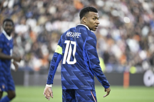 Soccer player with jersey number 10, name Mbappe, wearing a lime captain's armband on a blue patterned kit, on a stadium field