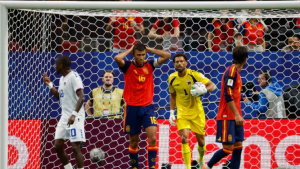 Spain soccer players react near the goal as the goalkeeper in yellow holds the ball inside the penalty area.
