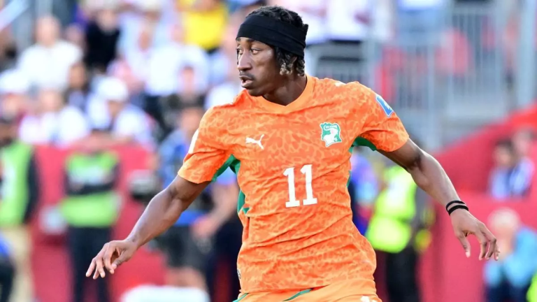 Soccer player in an orange jersey with number 11 and a black headband, mid-action on the field during a match.