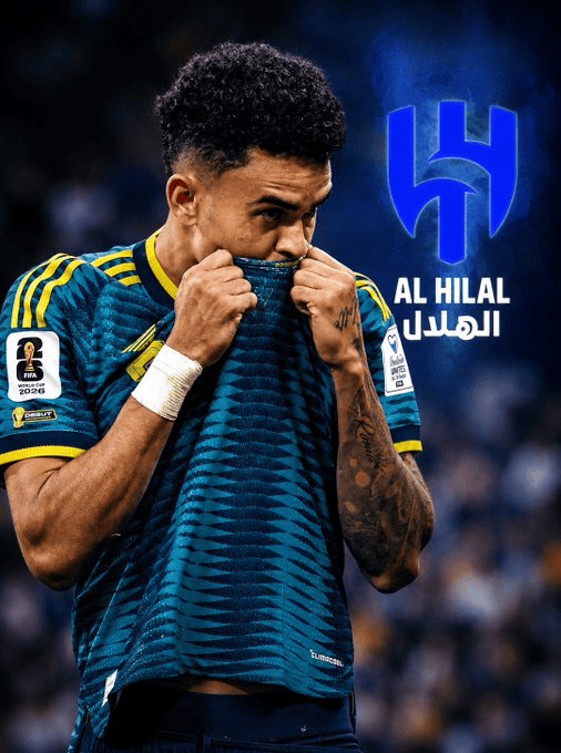 Soccer player in teal Al Hilal jersey pulls his shirt over his mouth, stadium crowd in background, logo and Arabic text visible on wall