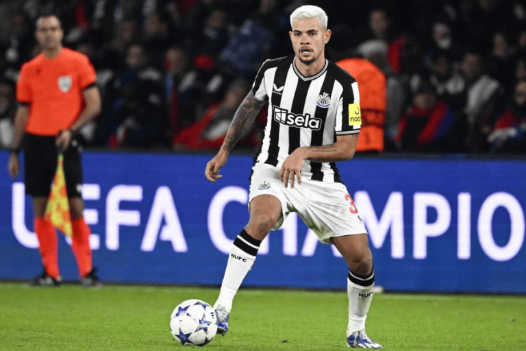 Soccer player in a black-and-white Newcastle United jersey dribbling the ball on the pitch during a UEFA Champions League match.