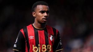 Male soccer player in a red and black striped jersey with a club crest, looking focused on the field.