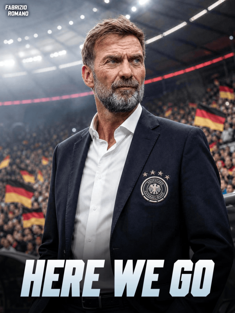 Man in a navy blazer with a German football federation badge stands on a crowded stadium field, fans waving German flags behind, 'HERE WE GO' at bottom.