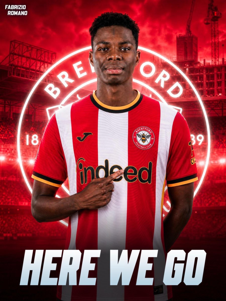 Brentford FC player in red-and-white striped kit, standing in a red stadium backdrop with 'Here We Go' text at the bottom.