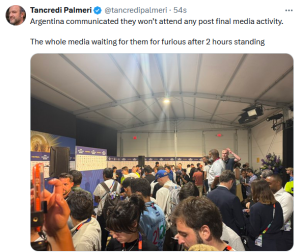 Crowded press area inside a large tent with reporters and photographers waiting for a briefing.