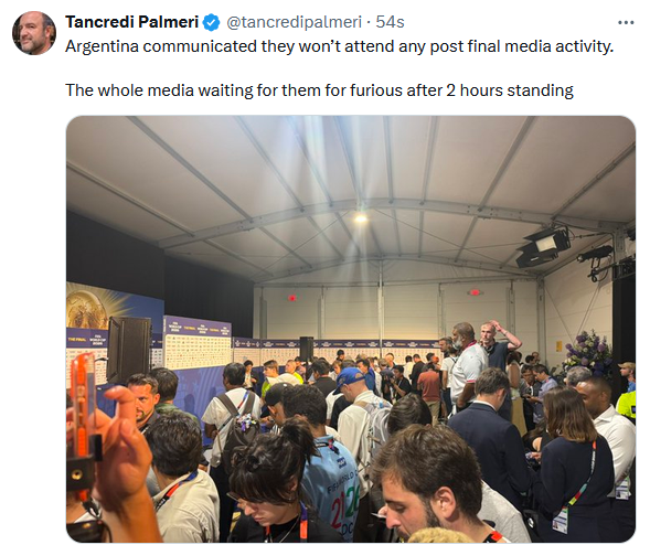 Crowded press area inside a large tent with reporters and photographers waiting for a briefing.