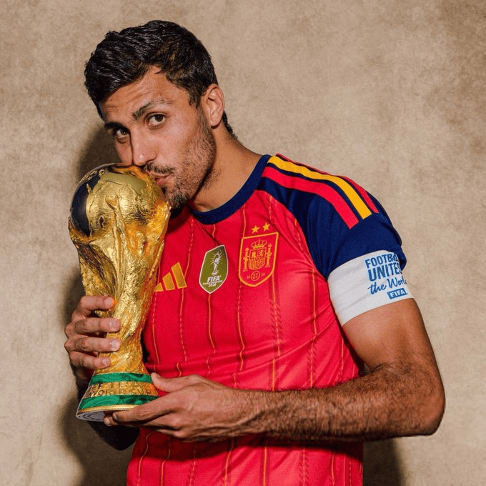 Footballer in a red Spain jersey kisses the FIFA World Cup trophy.