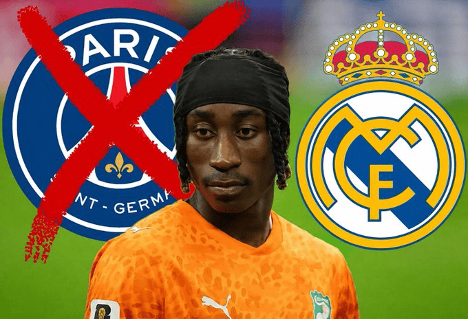 Young male footballer in an orange jersey stands between a crossed-out Paris Saint-Germain logo and the Real Madrid emblem, suggesting a transfer or exclusion context.