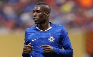 Male footballer in a blue Chelsea jersey running on the pitch during a match.