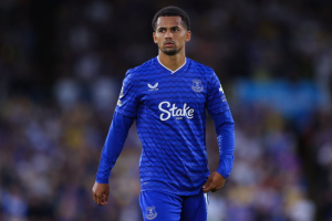 Soccer player in a royal blue Everton-style kit walking on the pitch with a focused expression, sponsor 'Stake' visible on chest.