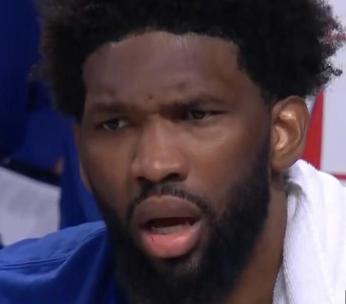 Close-up of a bearded man with a surprised or focused expression, wearing a blue shirt.
