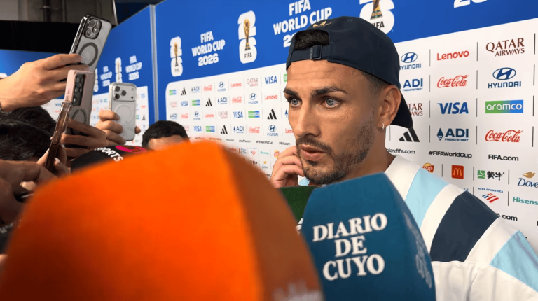 Soccer player wearing a backward cap being interviewed by reporters at a FIFA World Cup 2026 backdrop with sponsor logos visible behind him.
