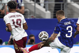 Two soccer players contest the ball: Lamine Yamal in a white jersey (19) and Digne in blue (3) during a match near the sideline.