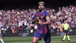Soccer player in Barcelona jersey celebrating a goal on the pitch with a cheering crowd behind him.